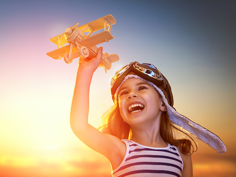 Image of a happy little girl holding a toy airplane